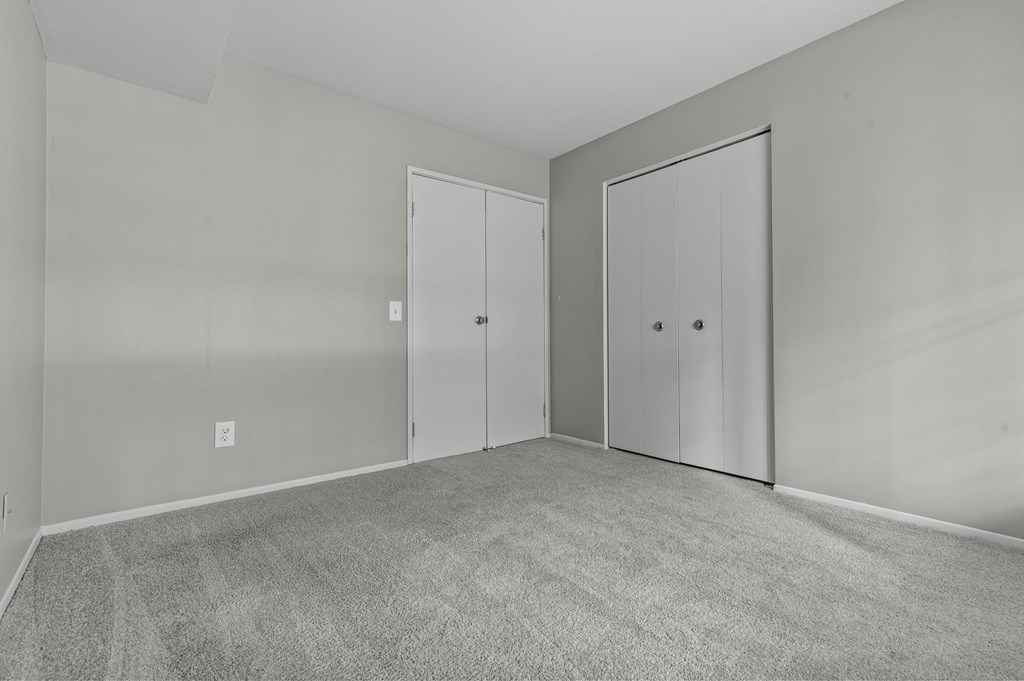 A room with two doors and carpeted floor.