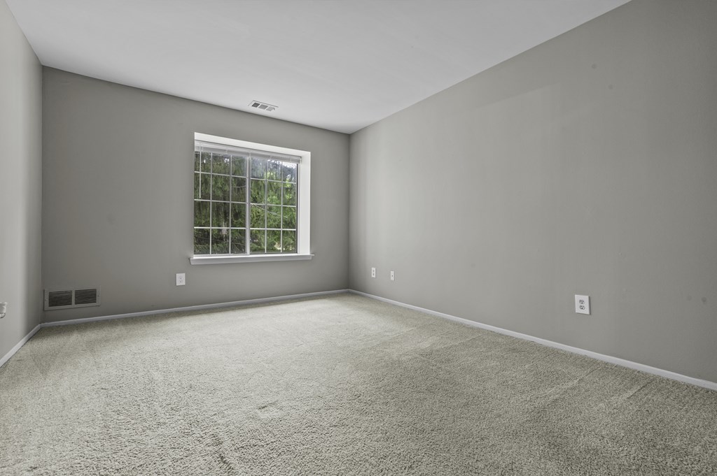 A room with a window and carpeted floor.