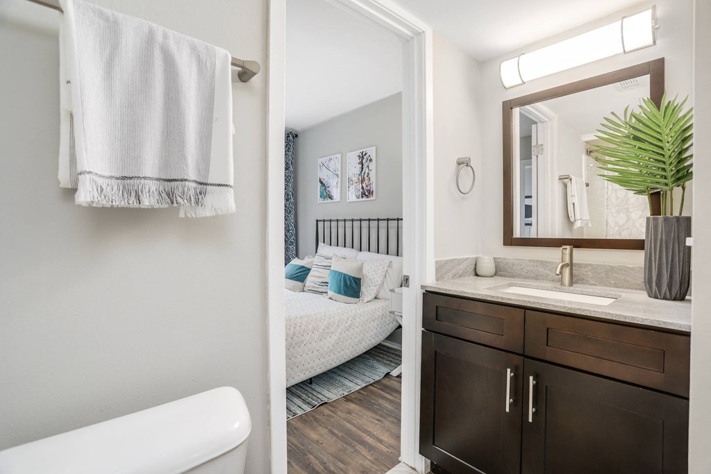 a bedroom and a bathroom with a sink and a mirror