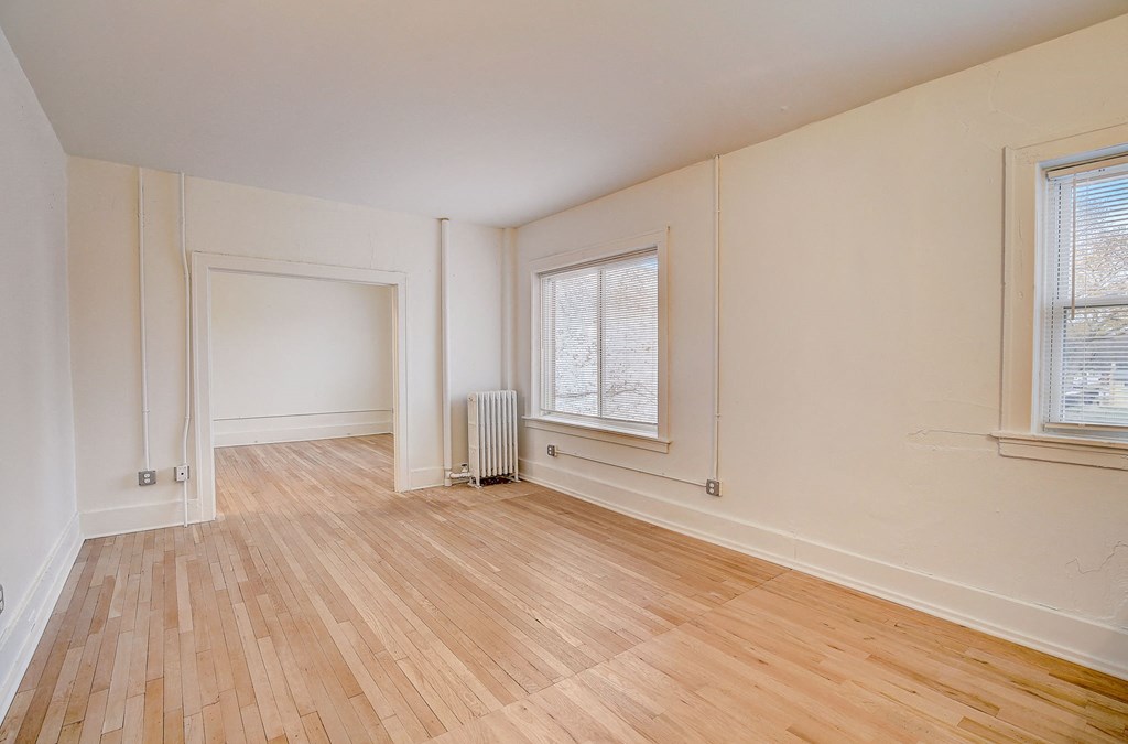 a living room with a hard wood floor and two windows