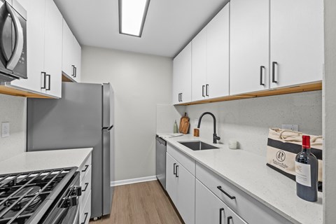A kitchen with white cabinets and a stainless steel refrigerator.