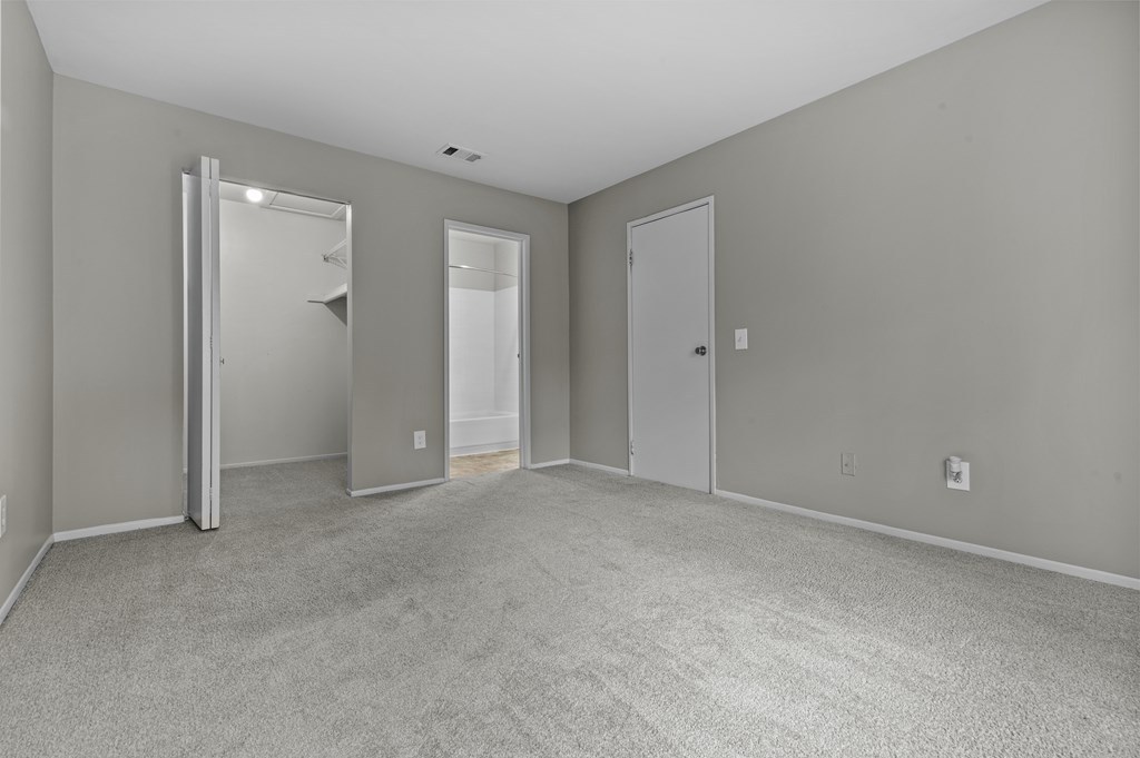 A large, empty room with a carpeted floor and two doors.