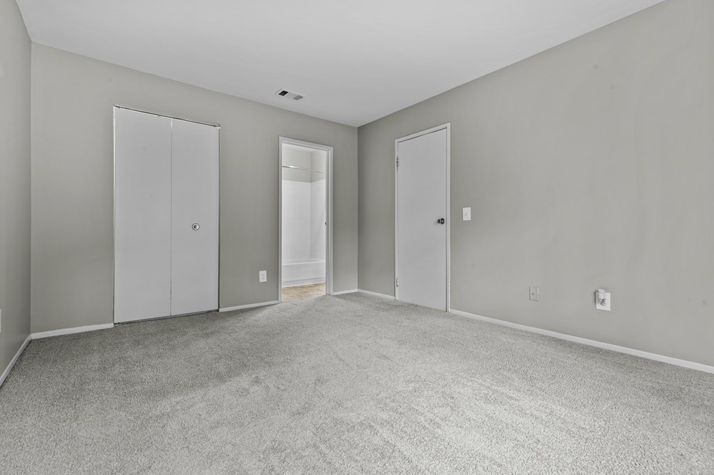 A room with grey carpet and white doors.