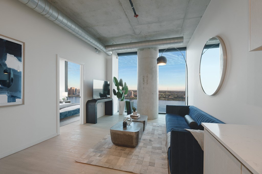 a living room with a blue couch and a table and a large window