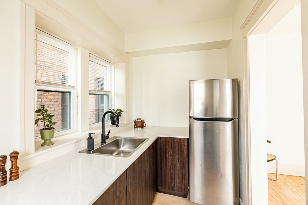 a kitchen with white countertops and a stainless steel refrigerator
