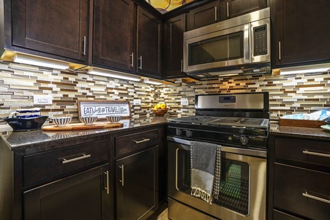 A kitchen with dark wood cabinets and a stove top oven.