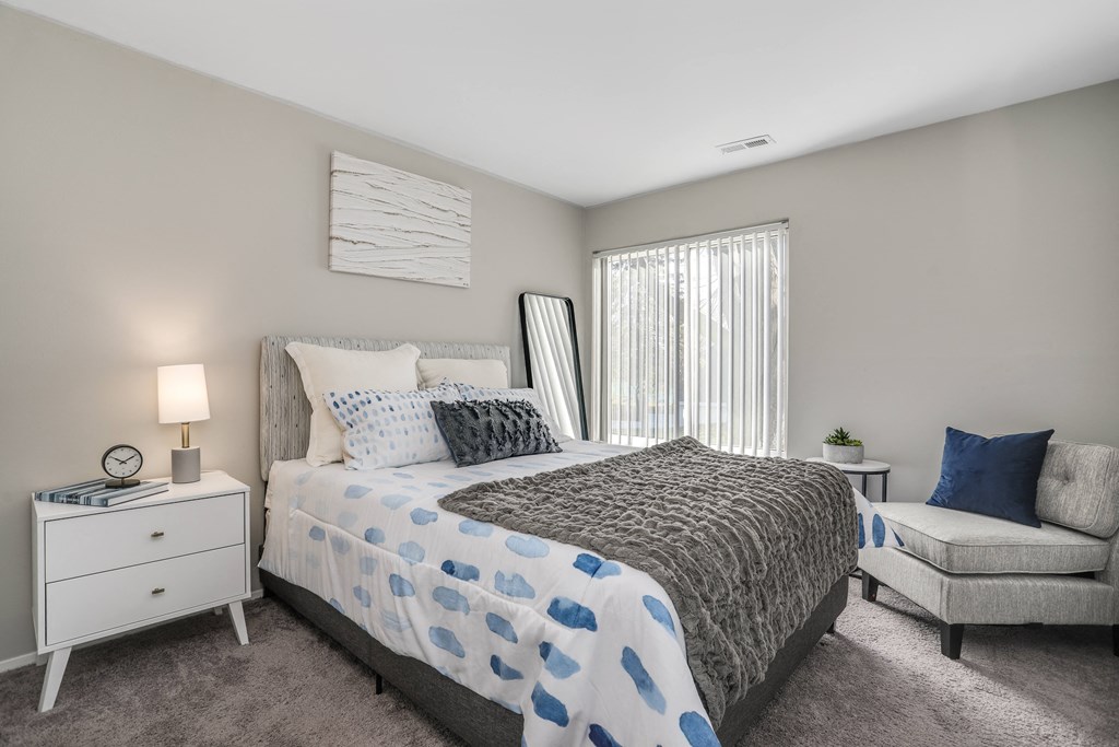 a bedroom with a bed and a chair and a window