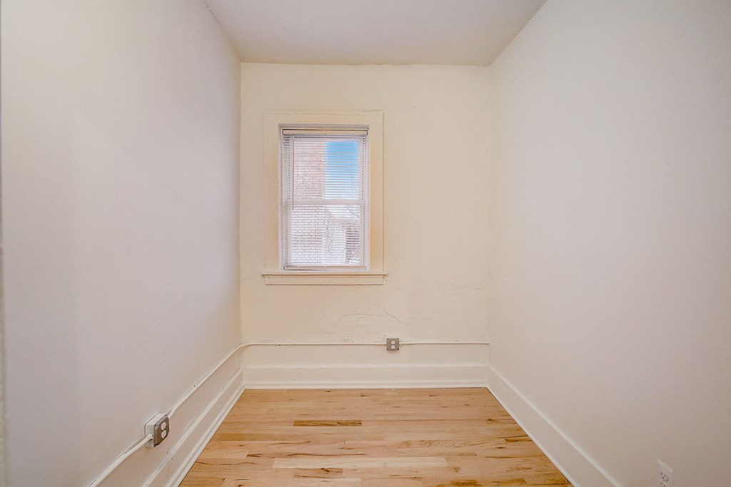 a bedroom with a wood floor and a window
