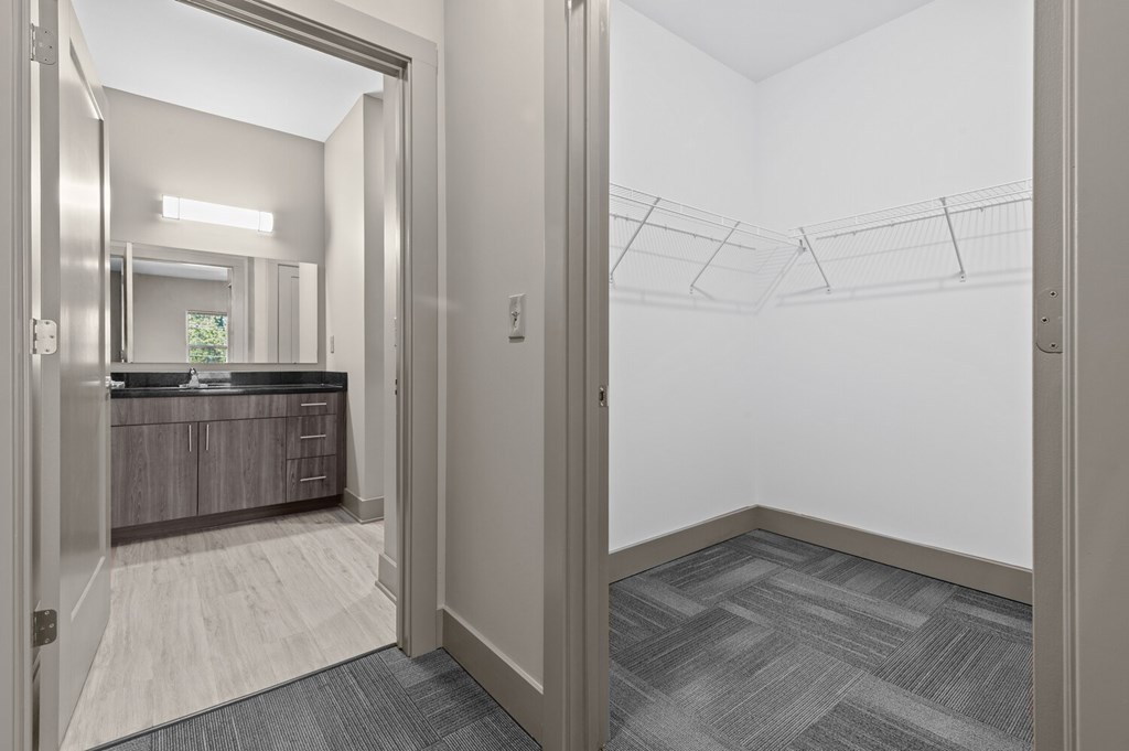 A hallway with a mirror and a door leading to a bathroom.