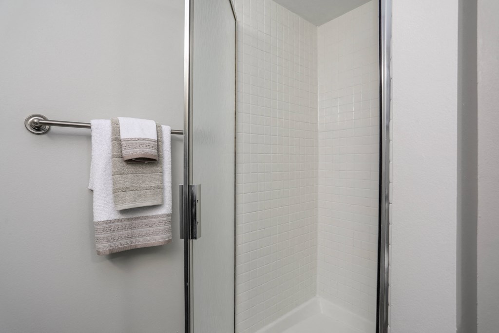a bathroom with a shower and a towel rack on the door