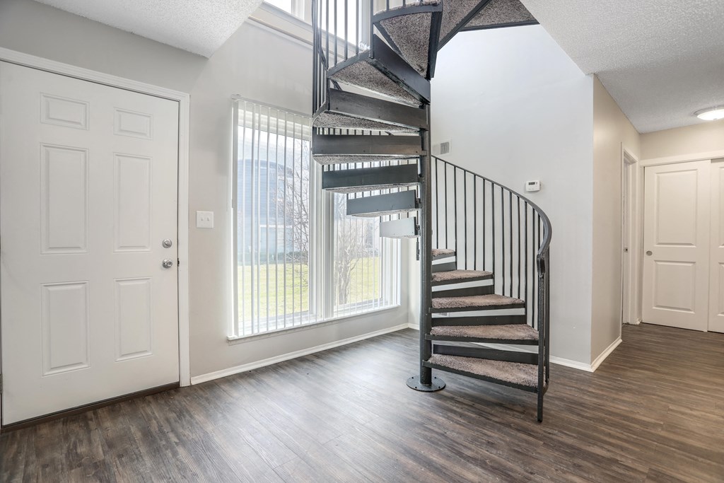 an empty living room with a spiral staircase in front of a window