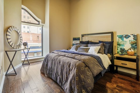 A bedroom with a large bed and a round mirror on a stand.