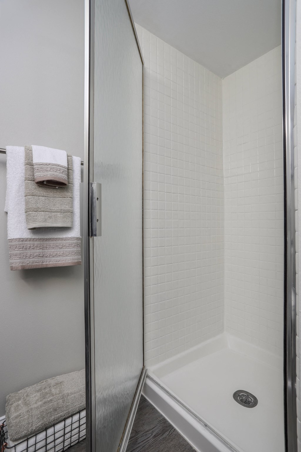 a shower in a small bathroom with towels on the rack