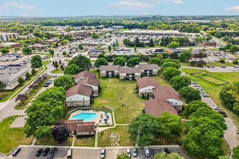 A bird's eye view of a residential area with houses, a swimming pool, and a parking lot.