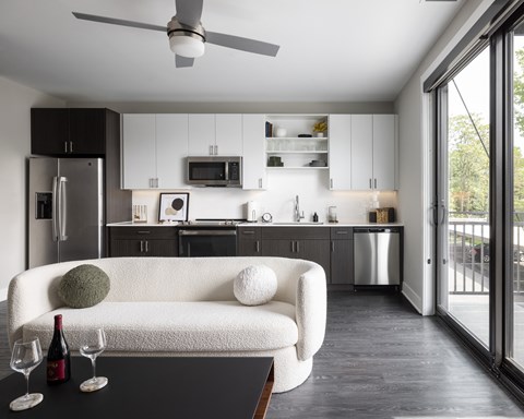 A modern kitchen with a white couch and a ceiling fan.at Flats at Iron Ridge, Michigan, 48220