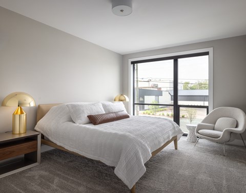 A bedroom with a large bed and a chair.