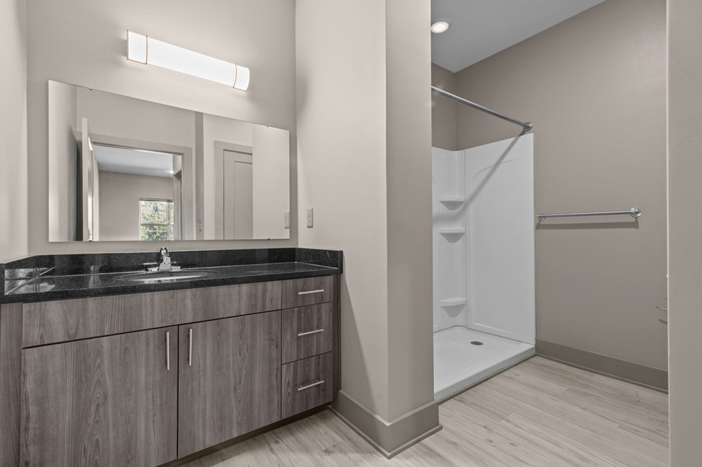 A bathroom with a sink, mirror, and shower.