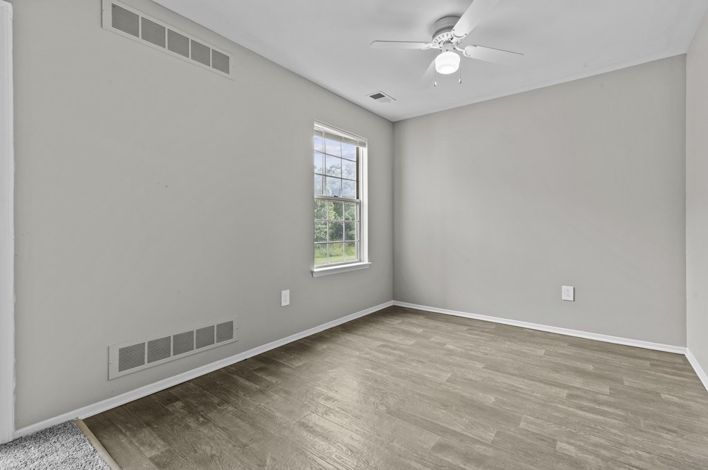 Empty room with a window and a ceiling fan.