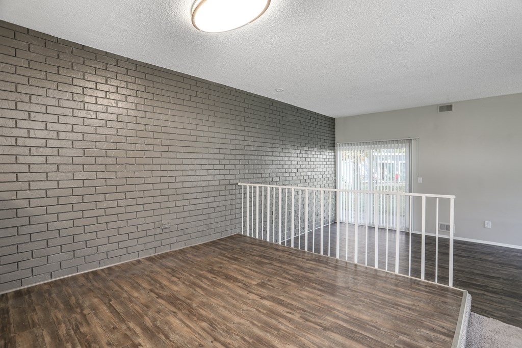 the living room of a house with a wood floor and a brick wall