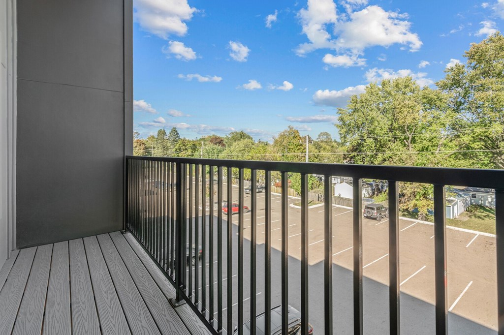A balcony with a black railing overlooks a parking lot.