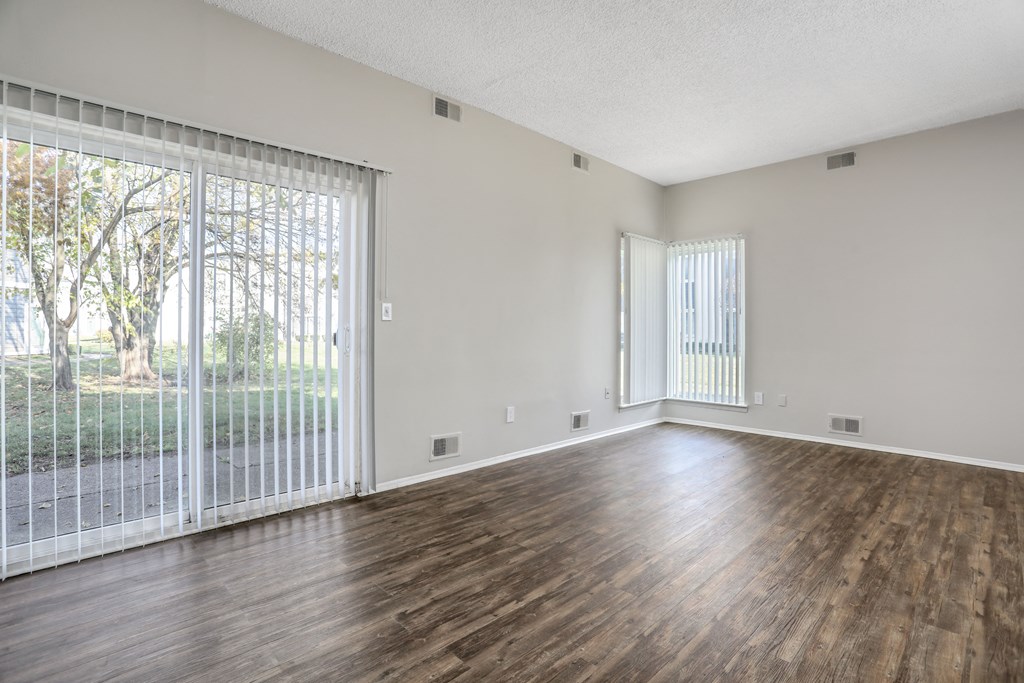 the living room of an empty apartment with wood flooring and a sliding glass door
