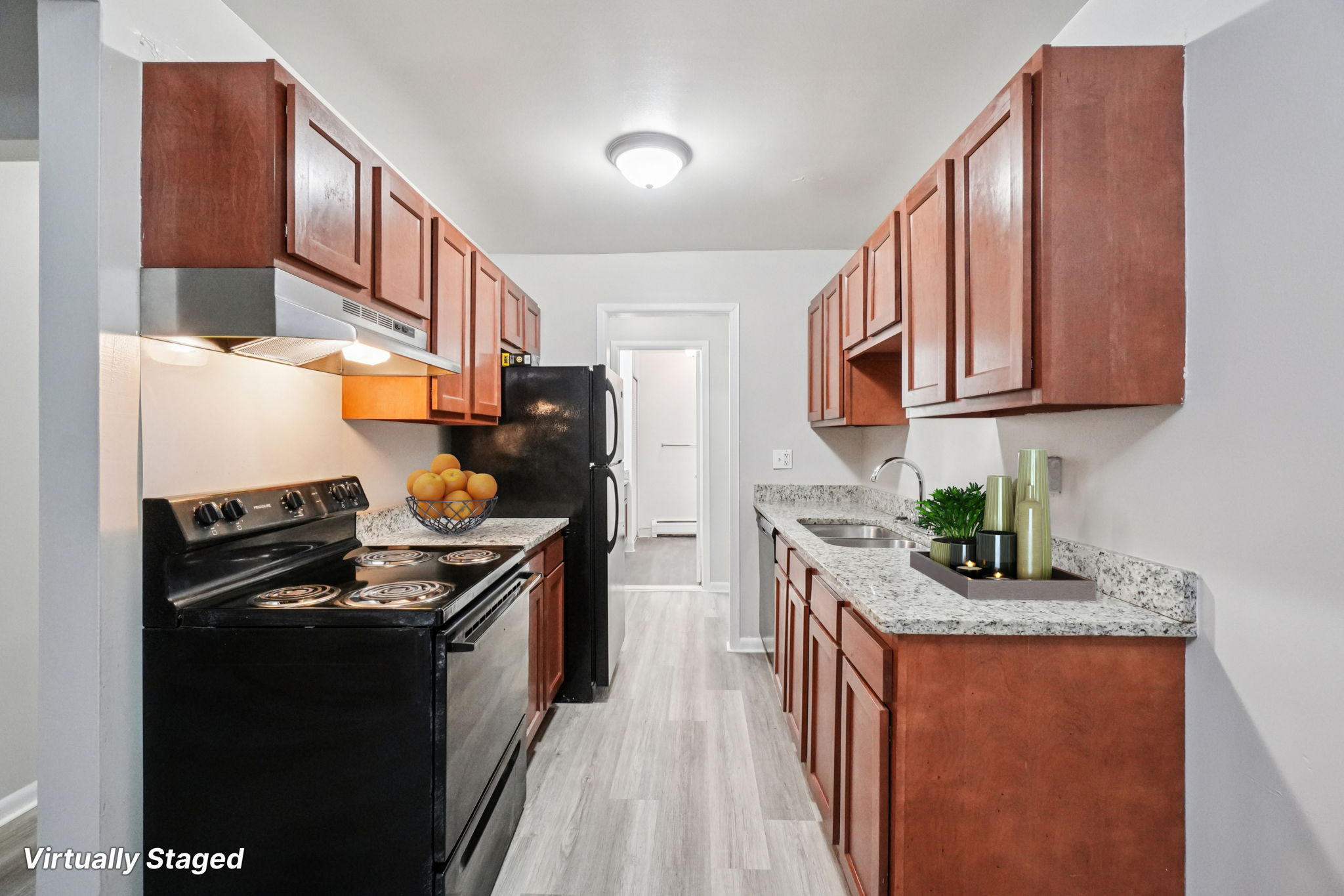 A kitchen with a black stove top oven and wooden cabinets.
