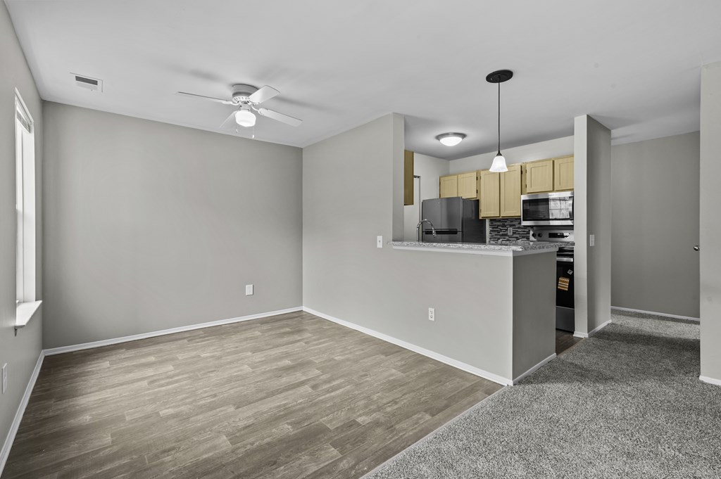 A spacious room with a kitchenette and a ceiling fan.