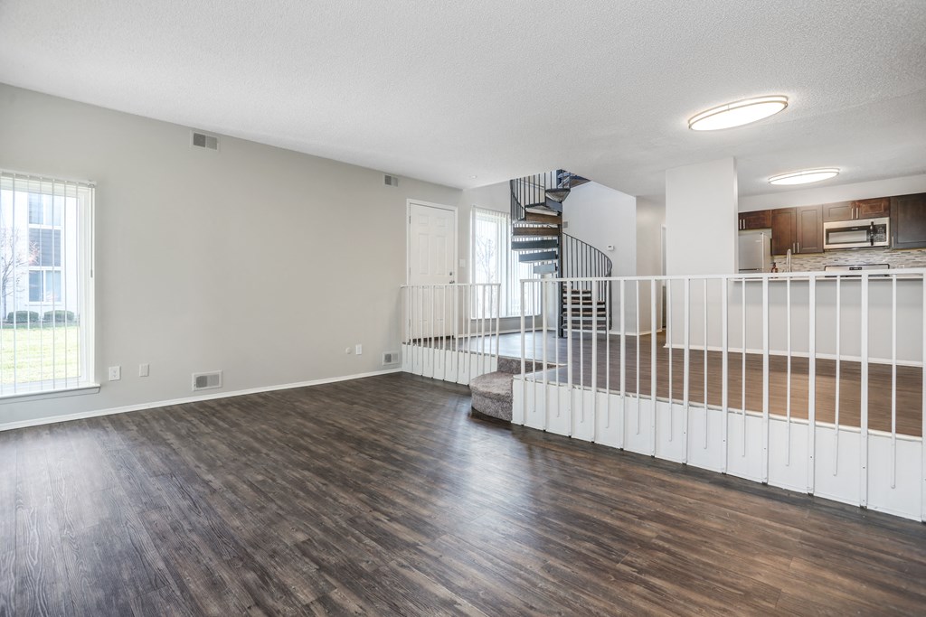 an empty living room with hard wood floors and a staircase
