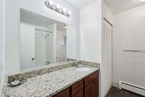 A bathroom with a granite countertop and a mirror above it.