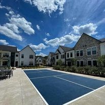 a blue tennis court in the middle of an apartment complex