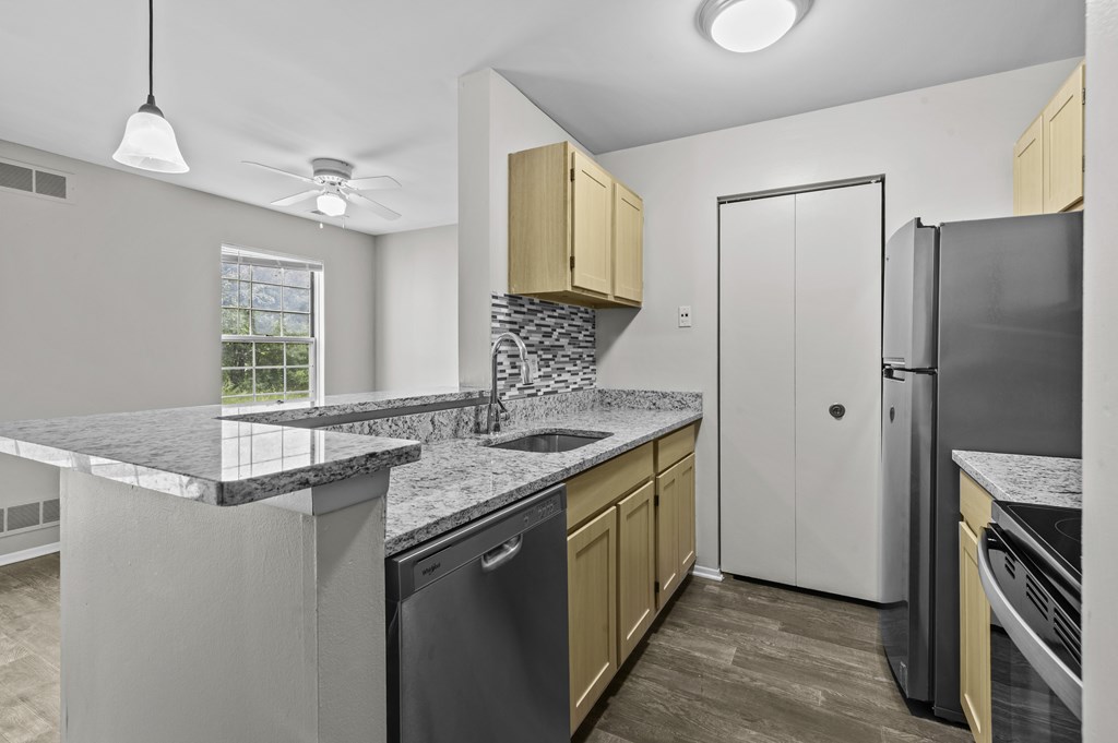 A kitchen with a black dishwasher and a white refrigerator.