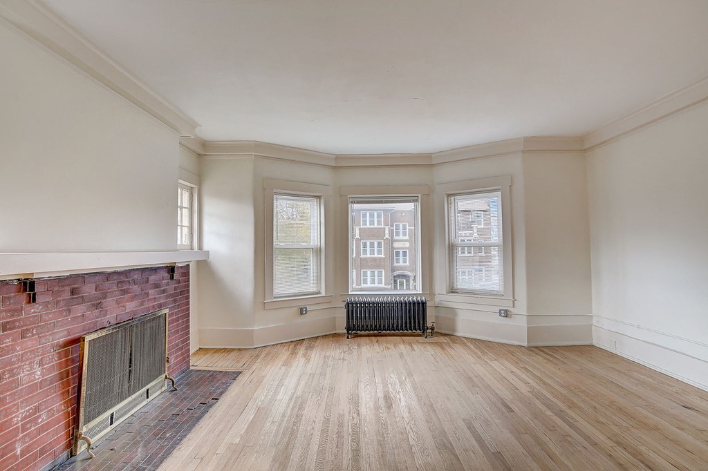 a living room with a hard wood floor and two windows and fireplace