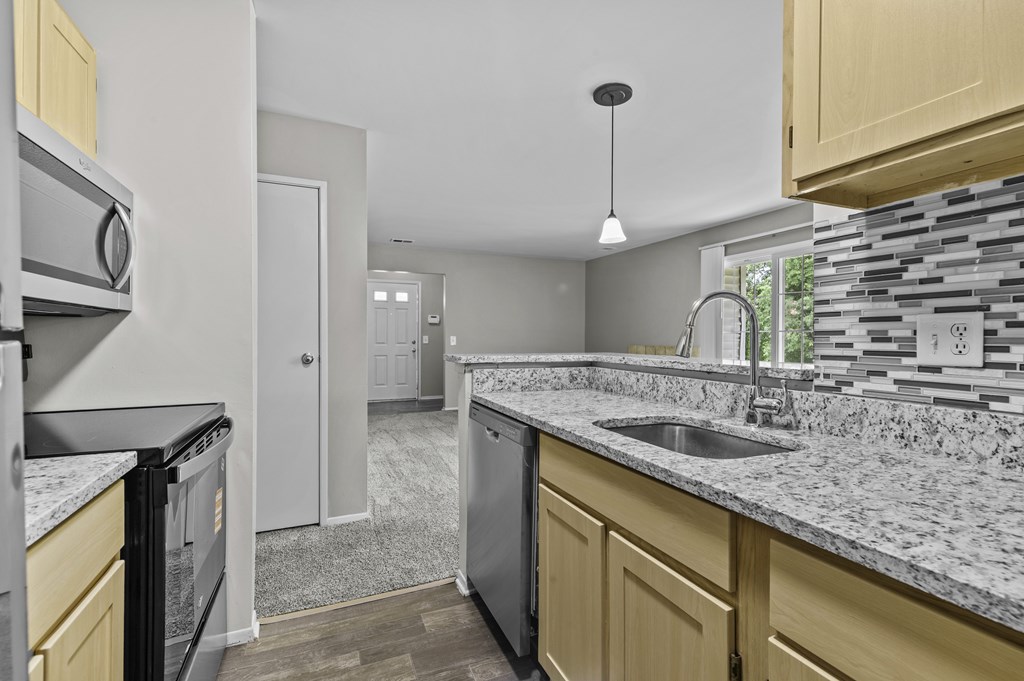 A kitchen with a black dishwasher and a black fridge.