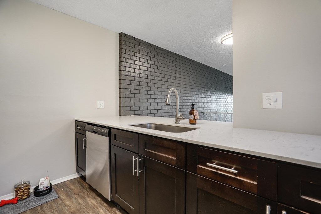 a kitchen with dark cabinets and a white counter top with a sink