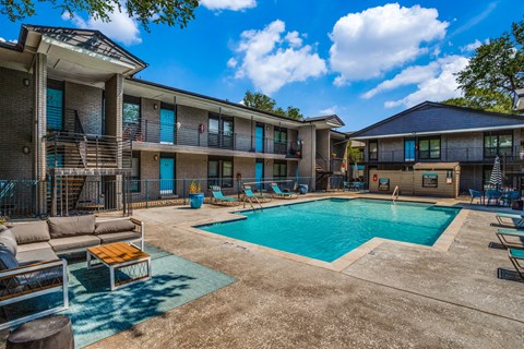 A swimming pool is surrounded by lounge chairs and umbrellas.