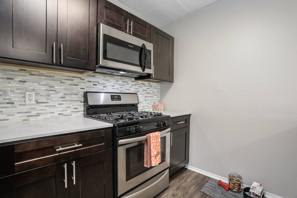 an empty kitchen with stainless steel appliances and wooden cabinets