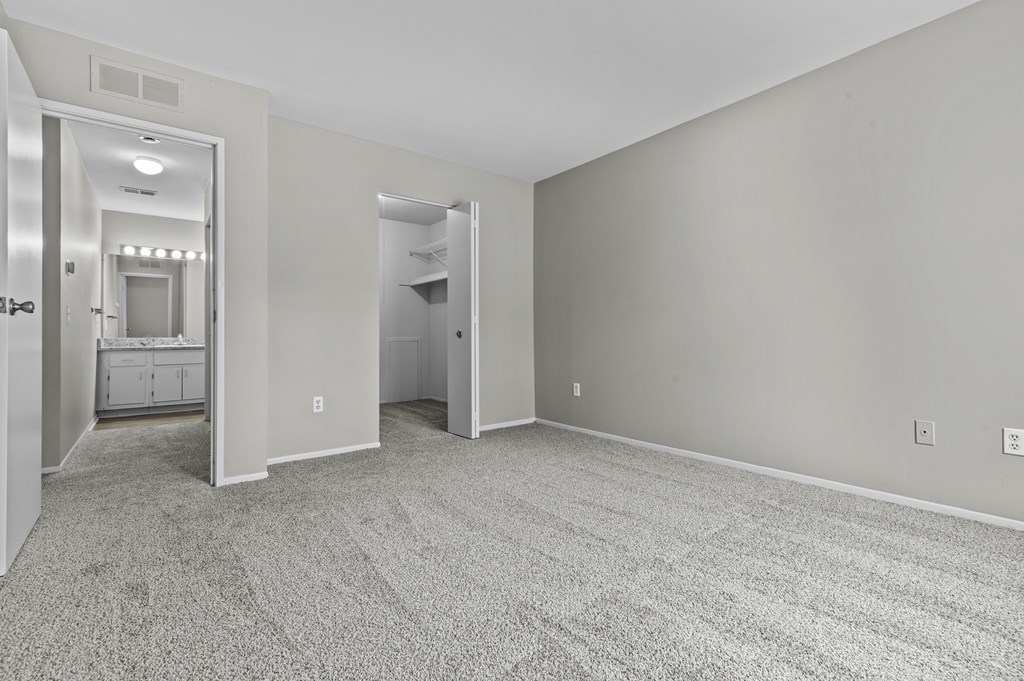 A spacious room with grey carpeting and two doors.