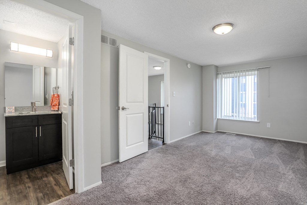 an empty living room and kitchen with a door to a hallway