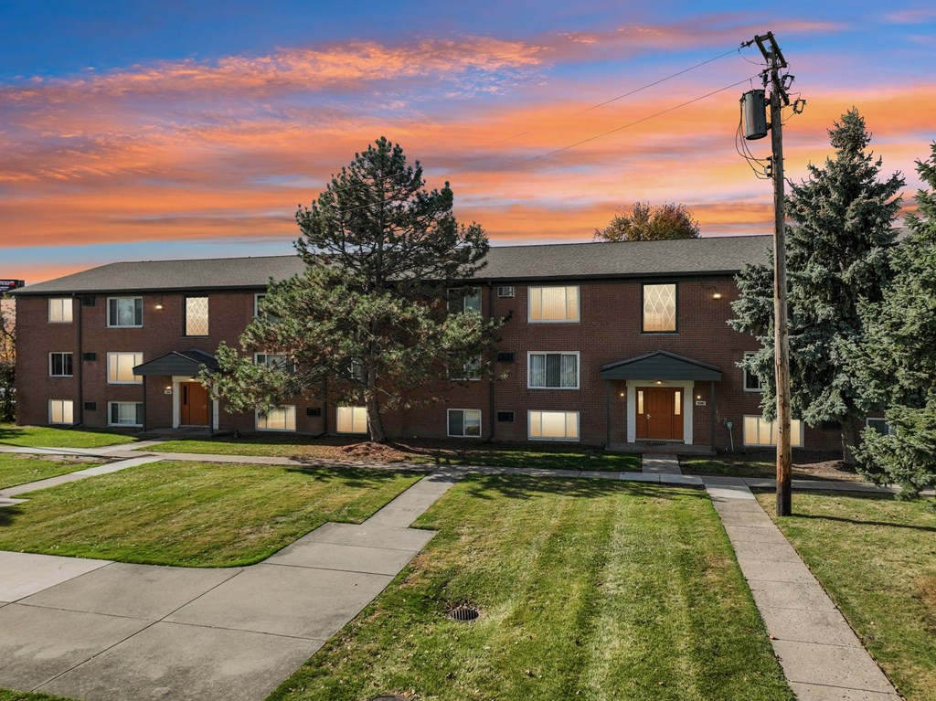 A building with a brown facade and a green lawn in front.