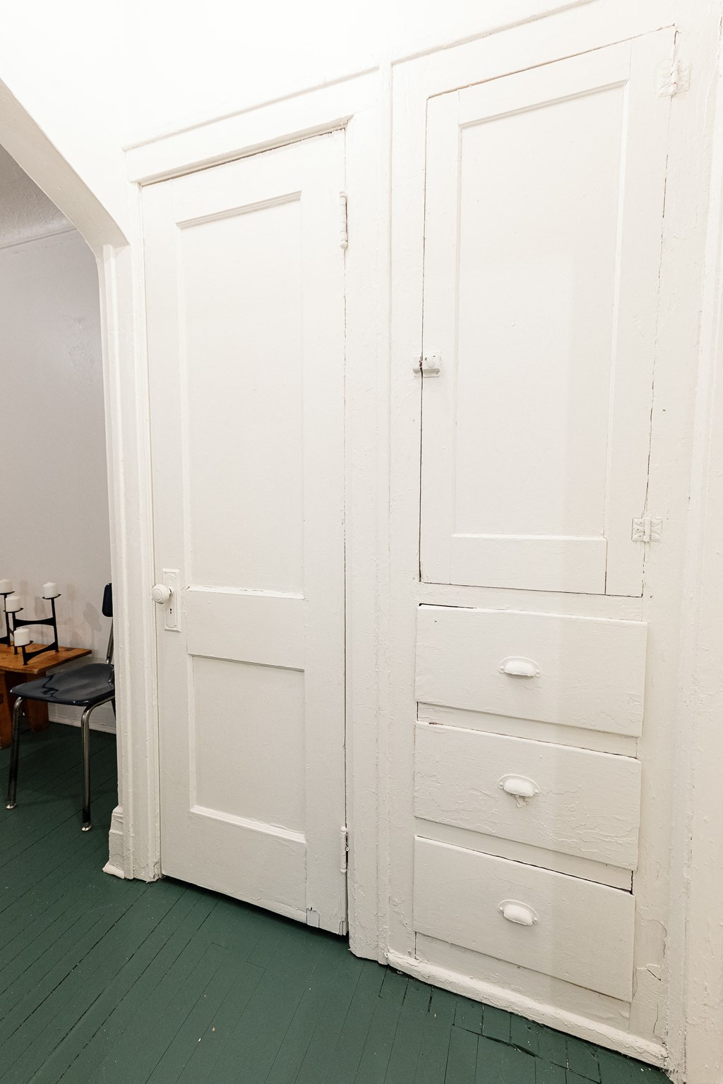 a pair of tall white closets in a room with green flooring