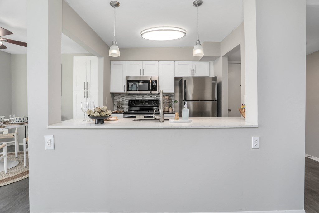 a kitchen with white cabinets and a counter top and a stainless steel refrigerator