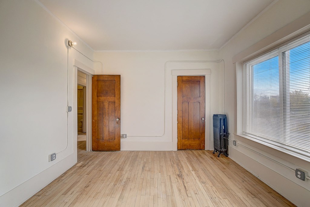 a bedroom with a hard wood floor and two windows and closet