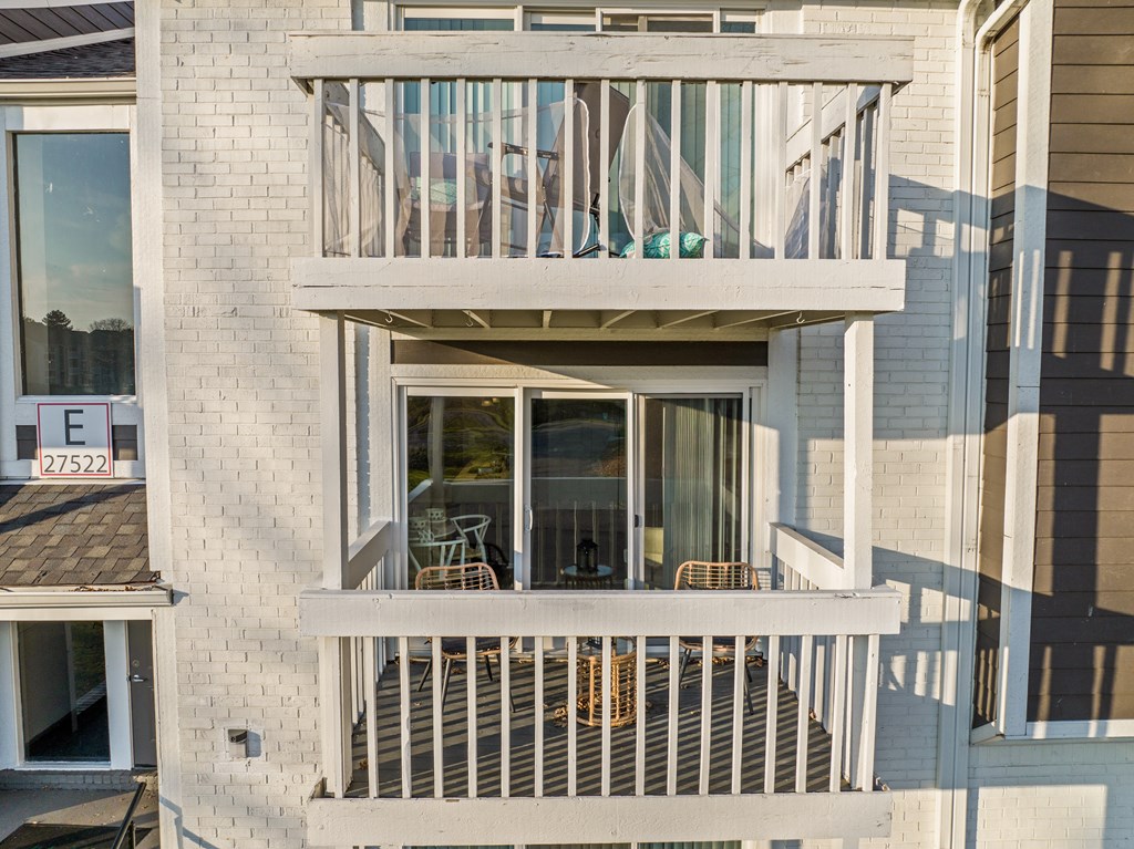 two balconies of a building with chairs and a table on a balcony