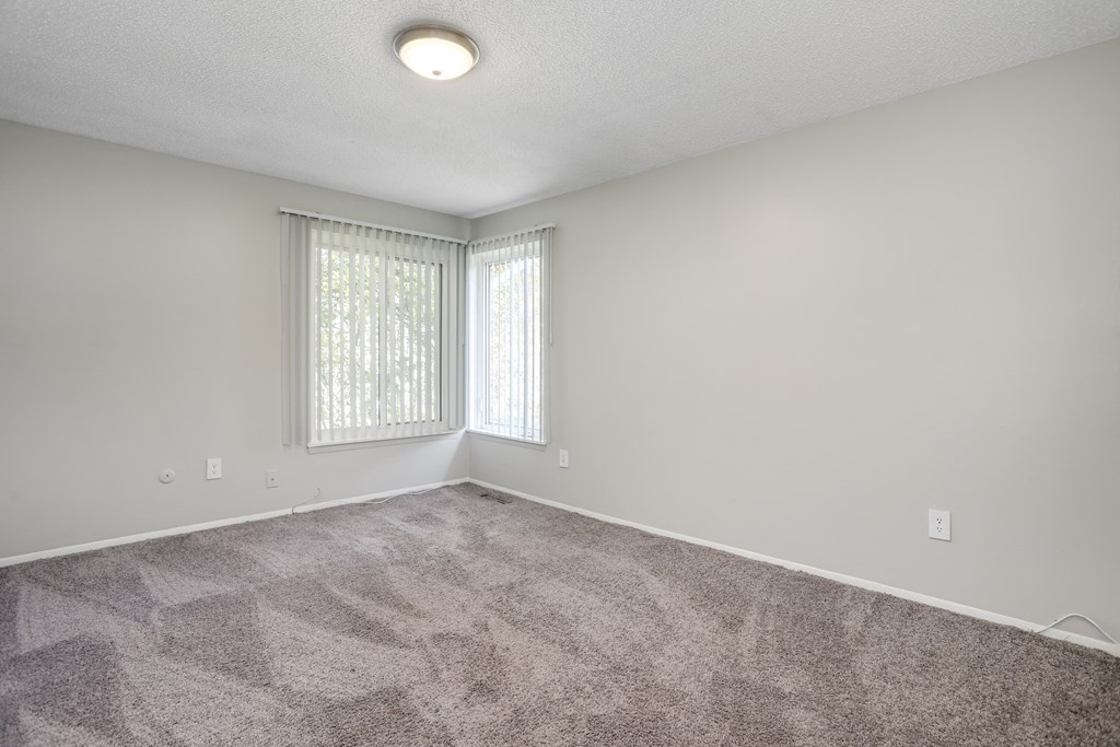 an empty living room with carpet and windows