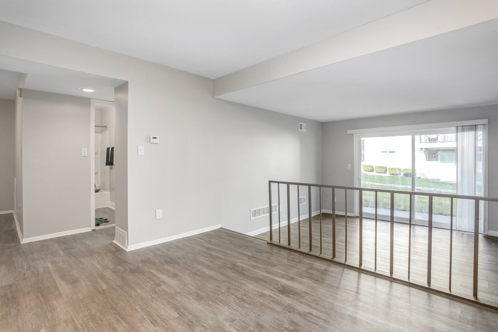 an empty living room with a balcony and a door to a hallway