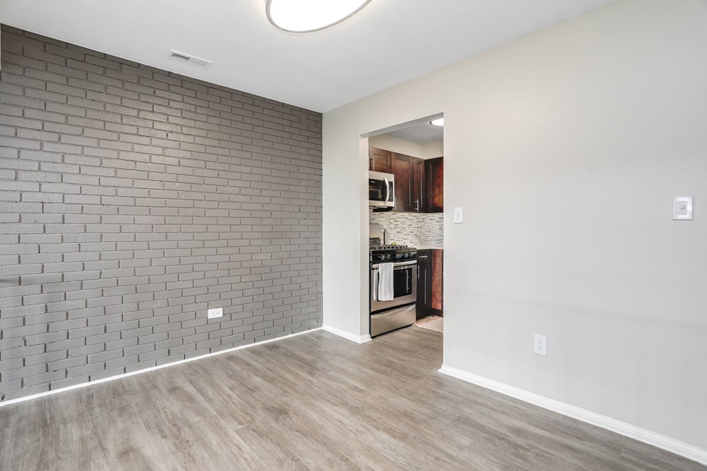 an empty living room with a kitchen in the background