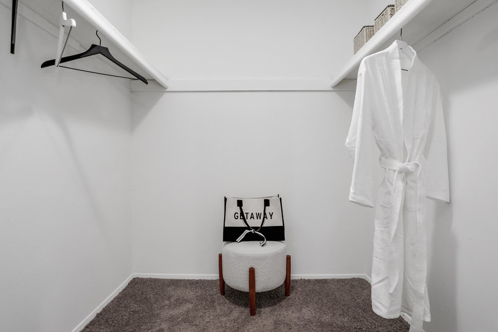 a white room with a white robe and a white chair and a closet