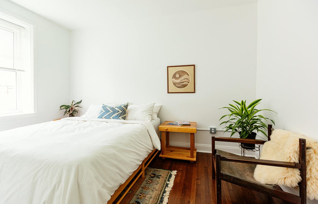 a bedroom with white walls and a bed with a white comforter
