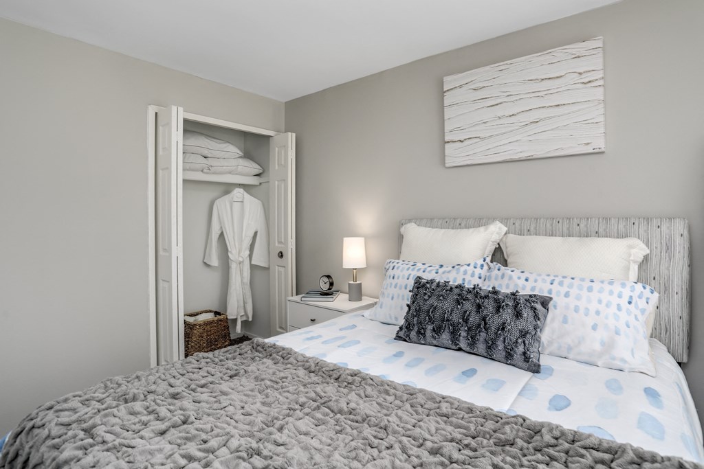 a bedroom with a bed and a closet with a white robe