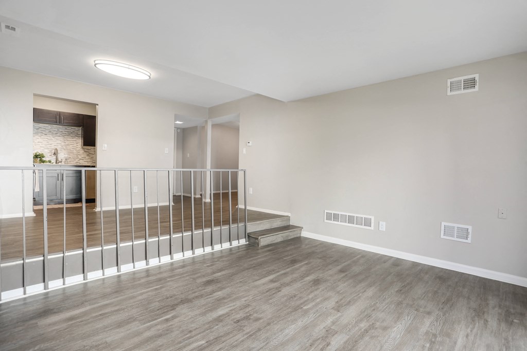 the upstairs living room and dining room of an apartment with wood flooring and railing